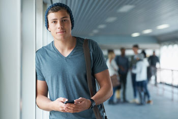 Student in Hochschule hat Smartphone in der Hand