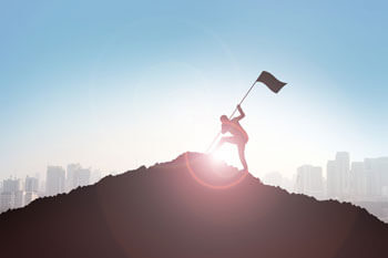 Ein Mensch stellt eine Flagge auf einen Berg