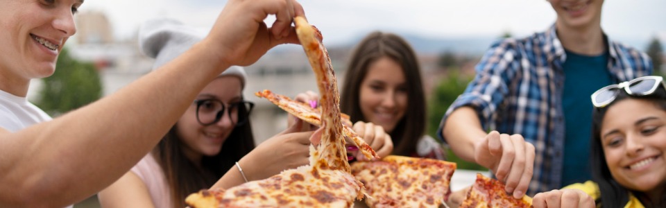 Studierende Freunde teilen sich im Freien eine Pizza