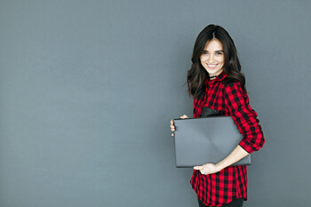 Studentin mit Laptop vor grauer Wand