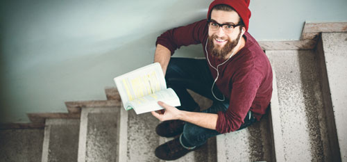Student sitzt mit Buch auf einer Treppe